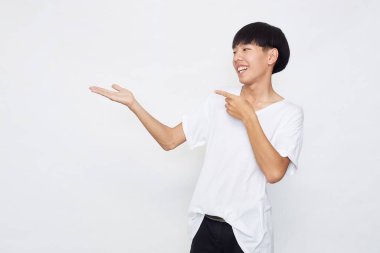 Yakışıklı genç Asyalı bir adam kameraya bakıp gülümserken elini beyaz arka planda gösteriyordu.