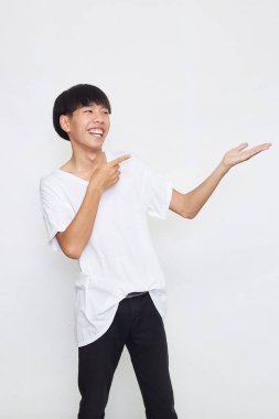 Yakışıklı genç Asyalı bir adam kameraya bakıp gülümserken elini beyaz arka planda gösteriyordu.