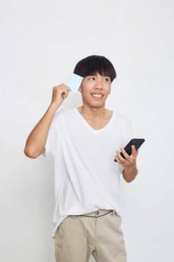 Cep telefonu tutan ve kredi kartını gösteren yakışıklı Asyalı genç bir adamın portresi.