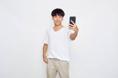 Boş uzaya telefon gösteren yakışıklı genç Asyalı adam izole edilmiş beyaz arka plan