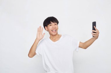 Boş uzaya telefon gösteren yakışıklı genç Asyalı adam izole edilmiş beyaz arka plan