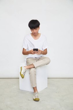 Yakışıklı Asyalı adam beyaz arka planda izole edilmiş telefonu kullanıyor. Boşluğu kopyala