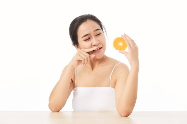 Mükemmel taze deri. Beyaz arka planda, dilimlenmiş portakallı, gülümseyen genç bir kadının portresi. Kadın Sağlıklı Kavram