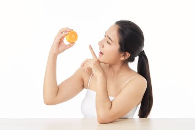 Mükemmel taze deri. Beyaz arka planda, dilimlenmiş portakallı, gülümseyen genç bir kadının portresi. Kadın Sağlıklı Kavram