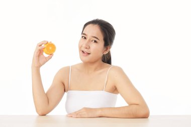 Mükemmel taze deri. Beyaz arka planda, dilimlenmiş portakallı, gülümseyen genç bir kadının portresi. Kadın Sağlıklı Kavram