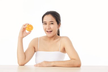 Mükemmel taze deri. Beyaz arka planda, dilimlenmiş portakallı, gülümseyen genç bir kadının portresi. Kadın Sağlıklı Kavram
