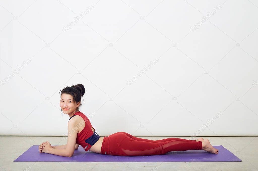 Young beautiful Asian woman making cobra pose on a yoga mat  at home, concept of healthy life and natural balance between body and mental development