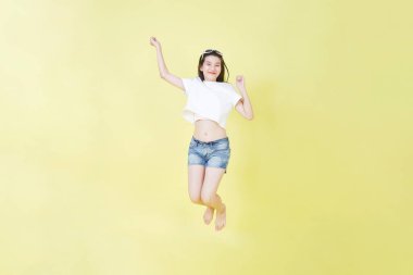 Yüzen, gülümseyen ve havada zıplayan güzel Asyalı bir kızın tam boy portresi.