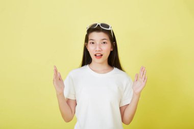 Genç zarif, güzel Asyalı kadın gülümsüyor ve boş fotokopi alanını işaret ediyor izole edilmiş sarı renkli arkaplan