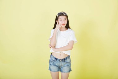 Genç zarif, güzel Asyalı kadın gülümsüyor ve boş fotokopi alanını işaret ediyor izole edilmiş sarı renkli arkaplan