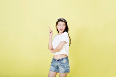 Genç zarif, güzel Asyalı kadın gülümsüyor ve boş fotokopi alanını işaret ediyor izole edilmiş sarı renkli arkaplan