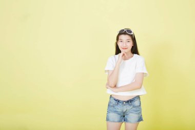 Genç zarif, güzel Asyalı kadın gülümsüyor ve boş fotokopi alanını işaret ediyor izole edilmiş sarı renkli arkaplan