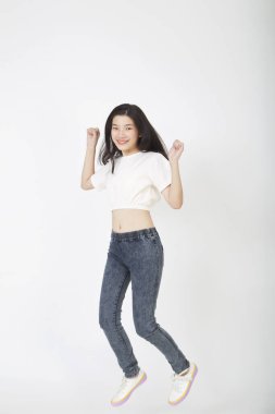 Okula geri dönüyorum. Genç, güzel Asyalı bir kız öğrenci beyaz arka planda zıplıyor.