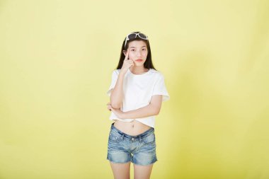 Sarı arka planı düşünen güzel Asyalı esmer kadının portresini kapat.