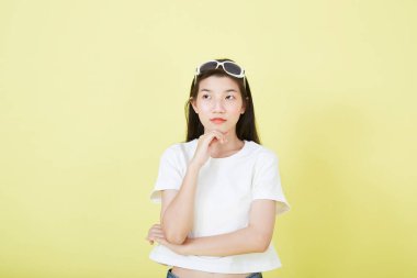 Sarı arka planı düşünen güzel Asyalı esmer kadının portresini kapat.