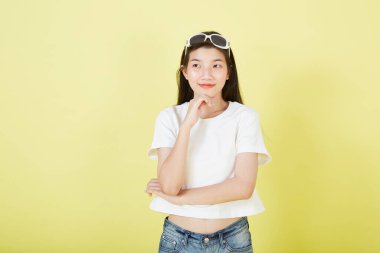 Sarı arka planı düşünen güzel Asyalı esmer kadının portresini kapat.