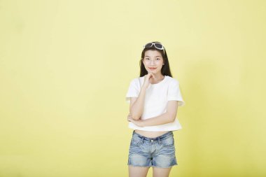 Sarı arka planı düşünen güzel Asyalı esmer kadının portresini kapat.