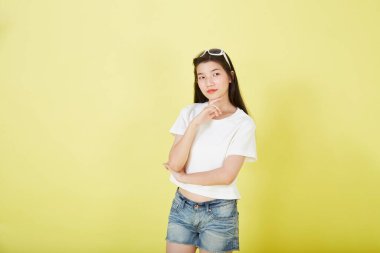 Sarı arka planı düşünen güzel Asyalı esmer kadının portresini kapat.