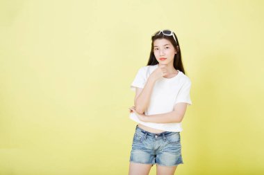 Sarı arka planı düşünen güzel Asyalı esmer kadının portresini kapat.