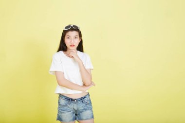 Sarı arka planı düşünen güzel Asyalı esmer kadının portresini kapat.