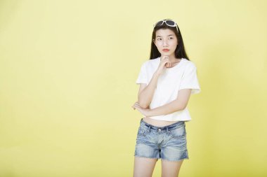 Sarı arka planı düşünen güzel Asyalı esmer kadının portresini kapat.