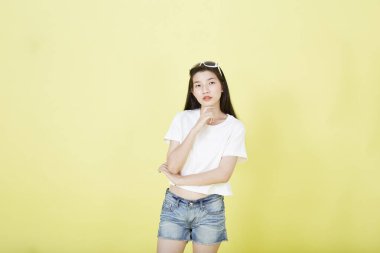 Sarı arka planı düşünen güzel Asyalı esmer kadının portresini kapat.