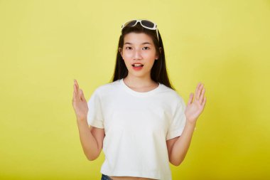 Genç ve güzel Asyalı kadın gülümseyip izole edilmiş sarı renkli arka planı işaret ediyor.