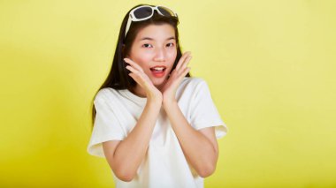 Genç ve güzel Asyalı kadın gülümseyip izole edilmiş sarı renkli arka planı işaret ediyor.