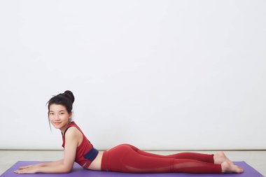 Genç Asyalı kadın arka planda egzersiz yapıyor.