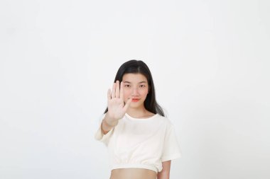 Gri arka planda avucu izole bir şekilde dur işareti yapan ciddi bir Asyalı kadının portresi.