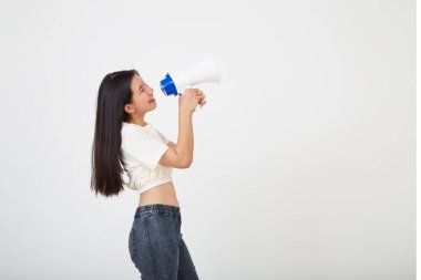 Neşeli genç Asyalı kadın izole edilmiş stüdyoda megafon anonsu yapıyor.