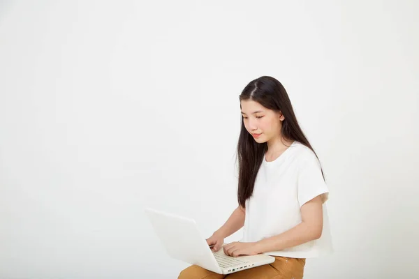 快乐迷人的年轻女性 带着笔记本电脑 盘腿坐着 在白色的工作室背景下看着空旷的空间 — 图库照片