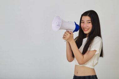 Asyalı güzel bir kadının portresi megafonla gülümseyerek izole edilmiş stüdyoda duyuru yapıyor.