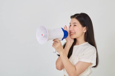 Asyalı güzel bir kadının portresi megafonla gülümseyerek izole edilmiş stüdyoda duyuru yapıyor.