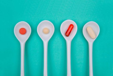 Cyan arka planında farklı haplarla dört kaşık 