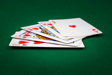 Kraliyet floşu yeşil bir keçede el ele poker oynuyor. 