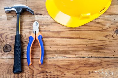 Tahta arka planda çekiç, göğüs uçları ve sarı kask.