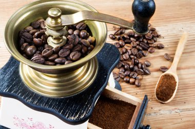 Elle kahve öğütücü, kahve çekirdekleri ahşap masada.