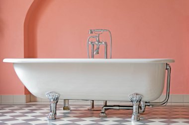 Retro tarzında zarif bir banyo. Büyük beyaz küvet, krom musluk. Lüks konutlarda banyo tasarımı