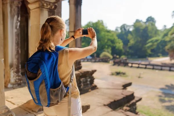 Young female tourist with smartphone taking picture of Angkor — Stock Photo, Image