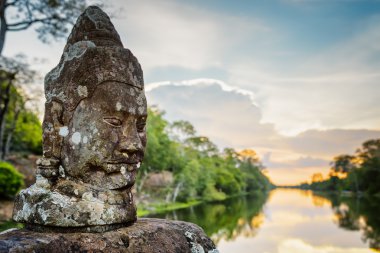 Yosunlu taş yüz Asura ve Angkor, Kamboçya hendek üzerinde gün batımı