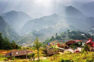 Hoang Lien Dağları'nda fırtınalı bulutlar aracılığıyla güneş ışığı ışınları