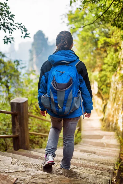 Joven turista femenina con mochila azul bajando escaleras — Foto de Stock