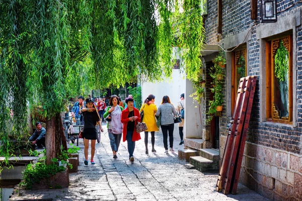 Turistas asiáticos están caminando en verde acogedora calle en Lijiang — Foto de Stock
