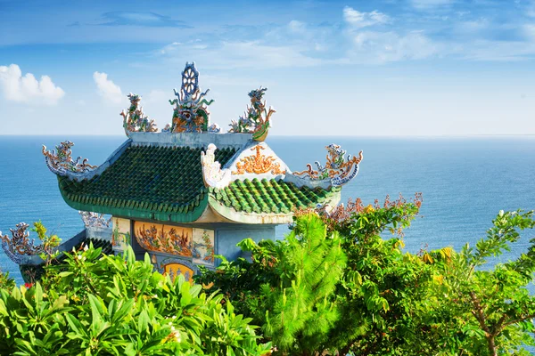 Tile roof of Buddhist temple among foliage on sea background — Stock Photo, Image