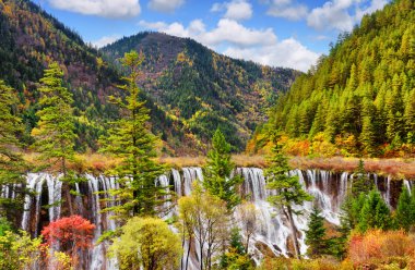 The Nuo Ri Lang Waterfall (Nuorilang) among woods and mountains clipart