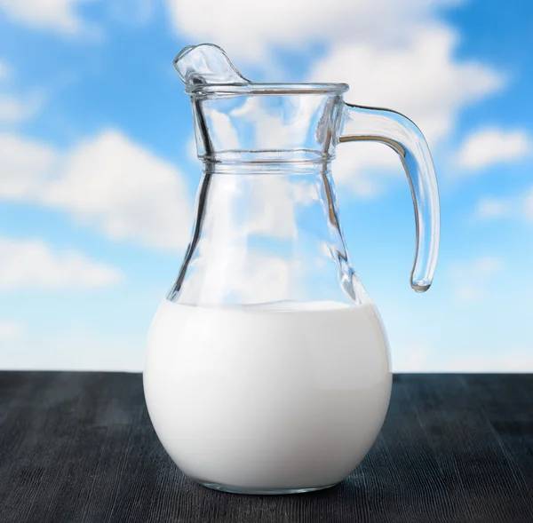 Gökyüzü arka plan üzerinde süt kabı. yarısı dolu sürahi — Stok fotoğraf