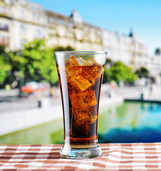 Glass of cola with ice on a table in cafe