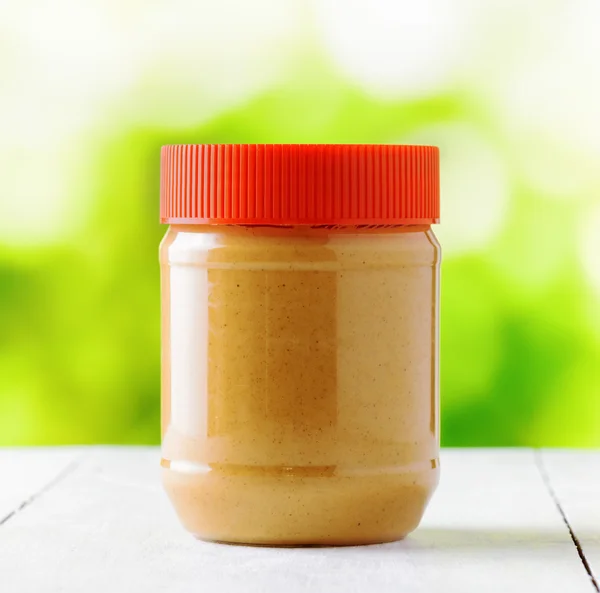 Jar of peanut butter on nature background — Stock Photo, Image