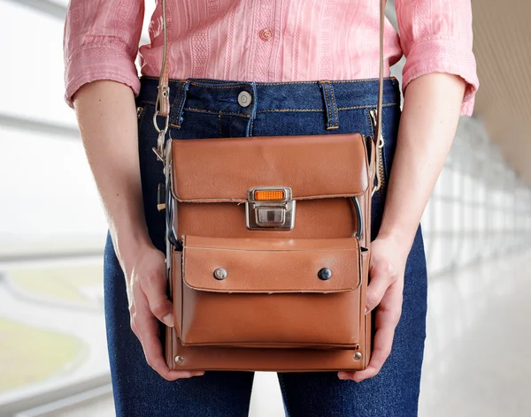 Young woman in deep blue jeans holding a bag